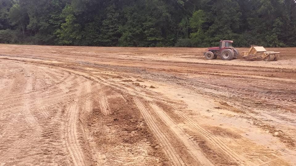 Tractor and land plane leveling a graded field
