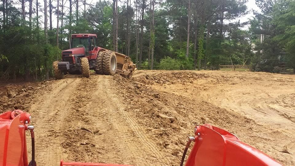 Land plane grading attachment leveling dirt on an active job site