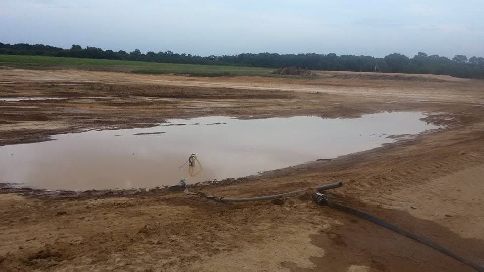 Freshly excavated pond filling with water during a pond building project
