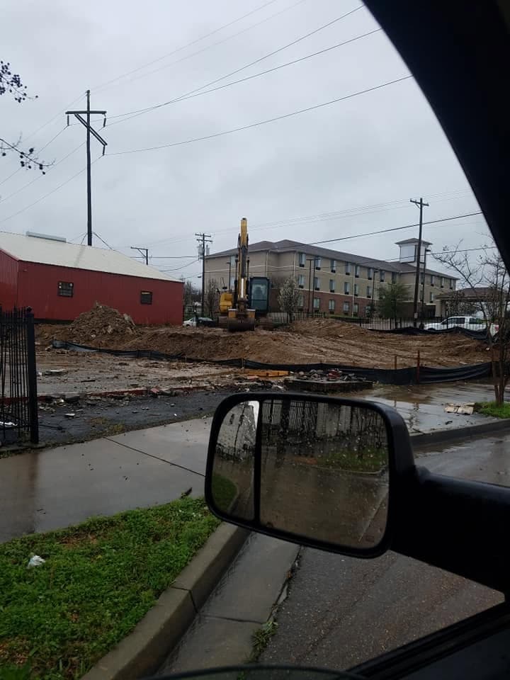 Excavator clearing a commercial lot for road and site development