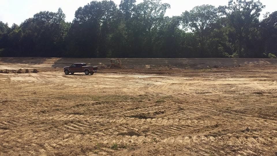 Truck parked beside a large cleared and graded field ready for construction