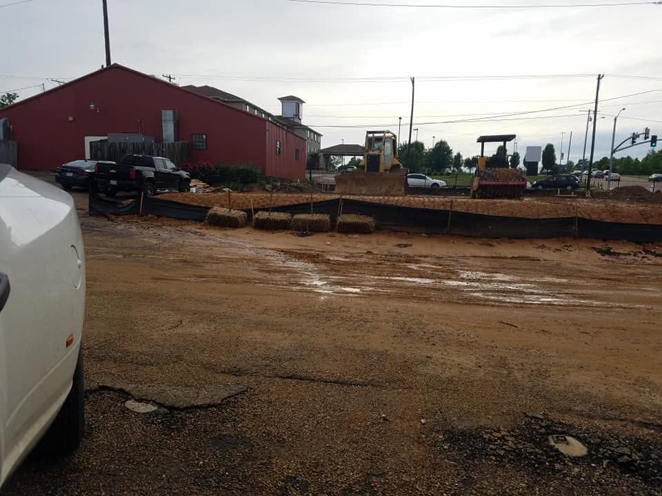 Site preparation equipment compacting a commercial lot