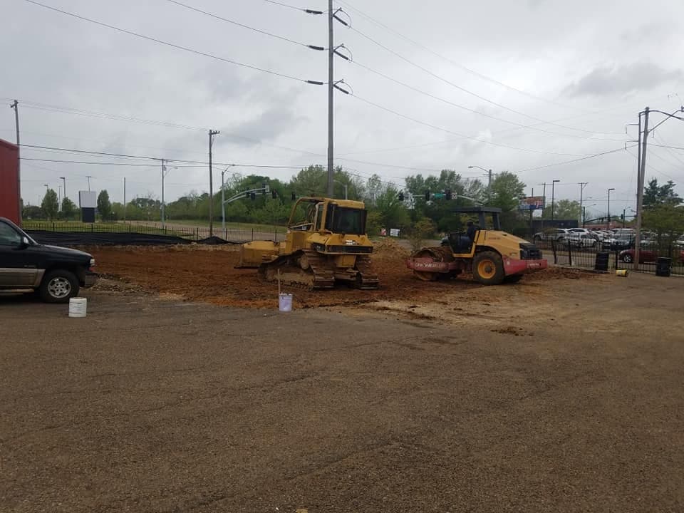 Bulldozer and roller compacting a commercial site pad